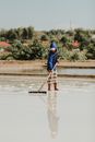 A salt farmer wearing a hood works on a salt farm in East Java, Indonesia.